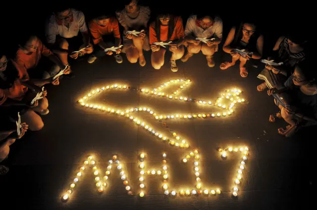 College students gather around candles forming the shape of an airplane, during a candlelight vigil for victims of the downed Malaysia Airlines Flight MH17, at a university in Yangzhou, Jiangsu province in this July 19, 2014 file photo.