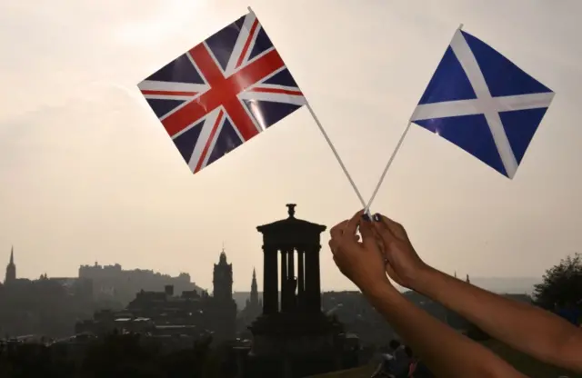 Union jack and Saltaire held up against the Edinburgh skyline