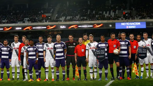 The opposing players and match officials pose with the "No to Racism" banners