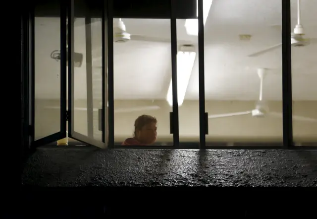 A resident, who was evacuated from her home, looks out through a window at the University of Puerto Vallarta, which is being used as a shelter, in the Pacific beach resort city of Puerto Vallarta,