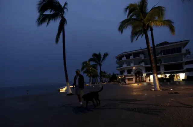 A man walks with his dog along the city"s historic boardwalk as Hurricane Patricia approaches the Pacific beach resort of Puerto Vallarta, Mexico October 23, 2015.