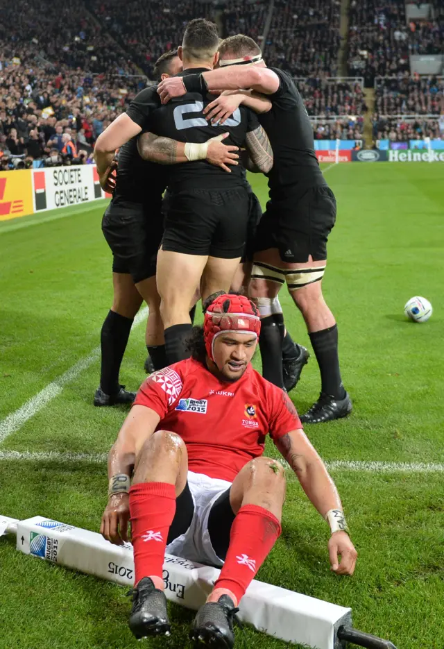 Latiume Fosita sits in front of the celebrating All Blacks