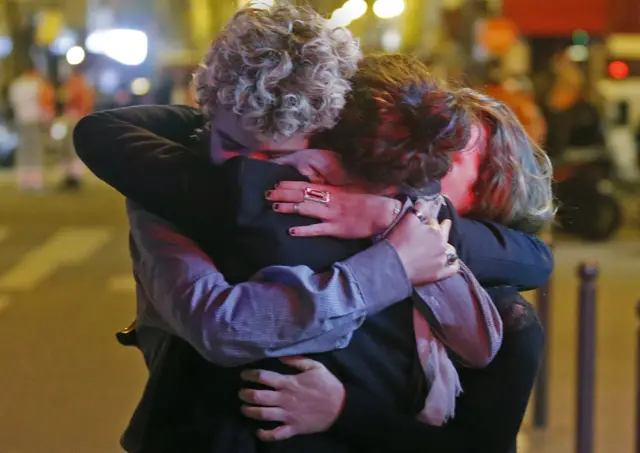 People hug on the street near the Bataclan concert hall