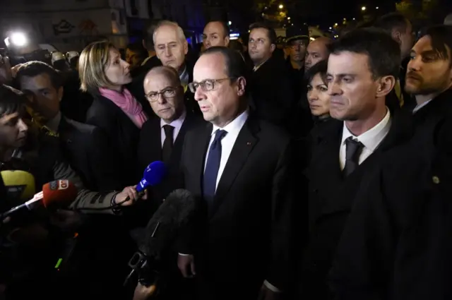 French President Francois Hollande (C), flanked by French Interior Minister Bernard Cazeneuve (L) and French Prime Minister manuel Valls (R) addresses reporters near the Bataclan concert hall in central Paris