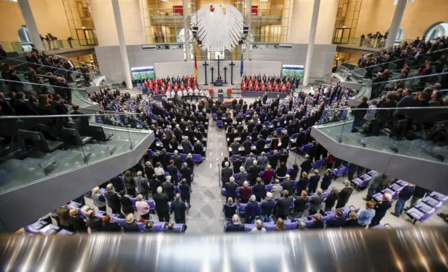 People hold a minute of silence in tribute to victims of Friday's attacks in Paris, during a ceremony marking the National Day of Mourning in the Bundestag in Berlin.