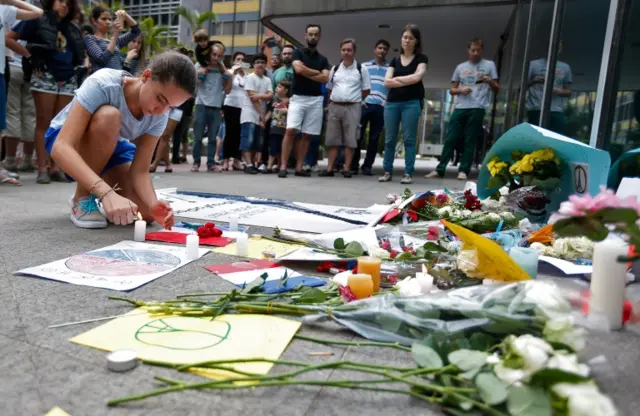 A girl lays flowers at a memorial in Sao Paulo