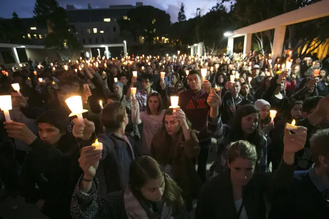 People hold candles at a vigil at California State University in memory of Nohemi Gonzalez, a design student killed in the attacks