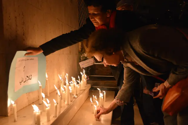 A woman lays a placard reading in Arabic "No to terrorism" during a candlelight vigil outside the French consulate in the Moroccan capital Rabat