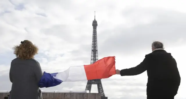 People holding french flag near the Eiffel tower