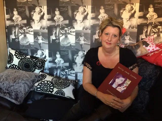 Holly's mother, Louise Clark, holds a remembrance book of her daughter