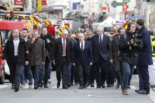 French Interior minister Bernard Cazeneuve (C) arrives in the security perimeter in Saint Denis