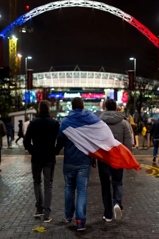 A French fan drapes a French flag over his shoulders