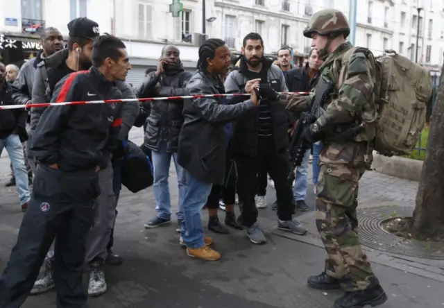 A French soldier checks the identity papers of a man in the area where shots were exchanged in Saint-Denis