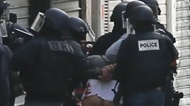 A man is arrested by police officers at the site were a raid happened in the city center of Saint Denis