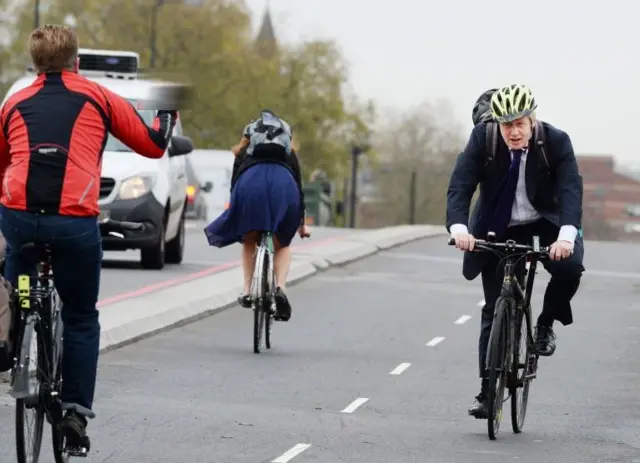 A cyclist gesticulates at Boris Johnson on his bicycle