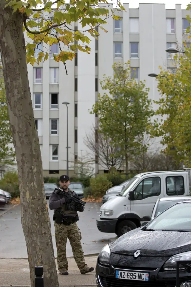 A soldier guards the building as police search the house of the mother of the female suicide bomber Hasna Aitboulahcen, in Aulnay-sous-Bois, near Paris