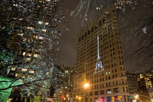 A projection of the Eiffel Tower is displayed on the side of New York City"s Flatiron building