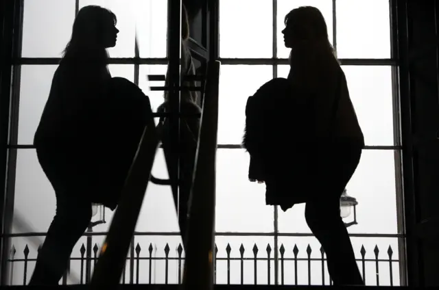 Woman in shadow faces a mirror