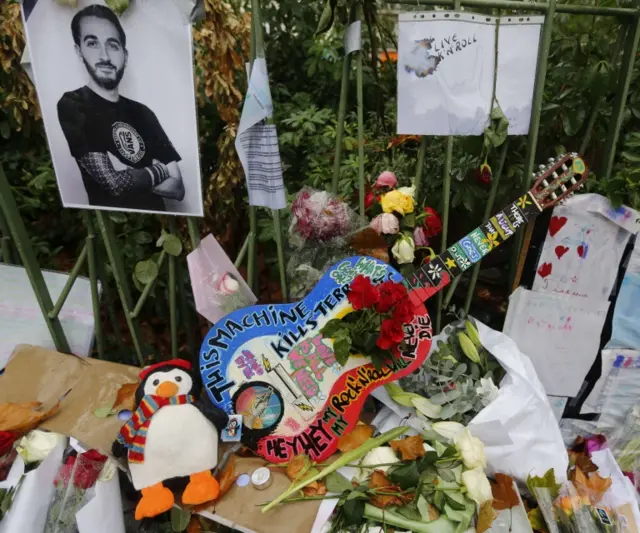 A guitar with messages and the blue, white and red colours of the French flag, is seen among flowers in tribute to victims near the Bataclan concert hall