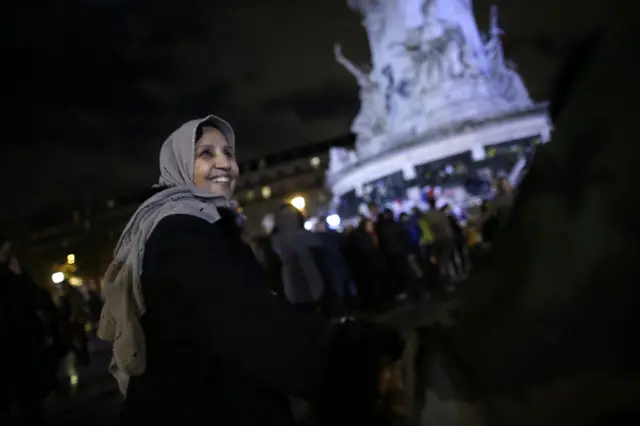 A woman wearing a head scarf smiles