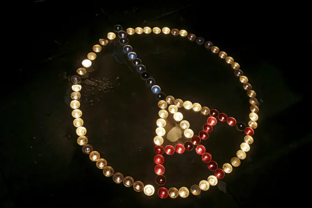 Candles are laid on the "Republique" square in the shape of the Eiffel tower and the peace sign in the French capital, in Paris