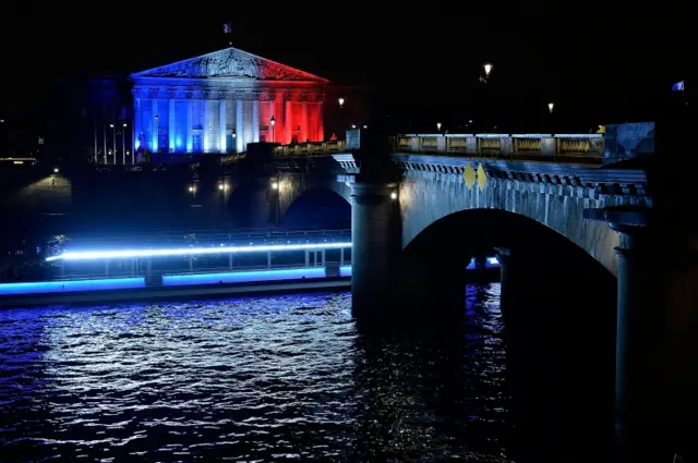 The French Parliament is illuminated in the colours of the French flag