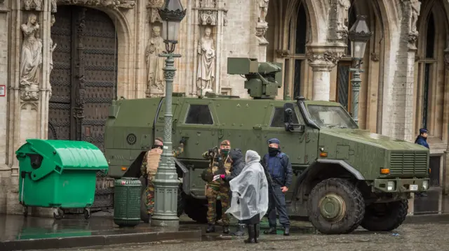 Armed military men stand guard next to a truck stationed at the Grand Place in front of the City Hall in Brussels.