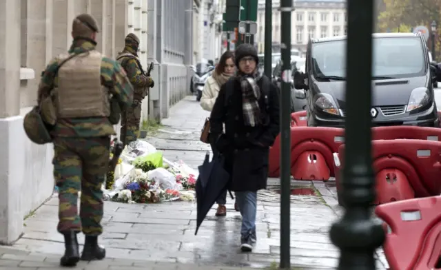 Belgian soldiers patrol next to flowers left outside of the French Consulates office in Brussels