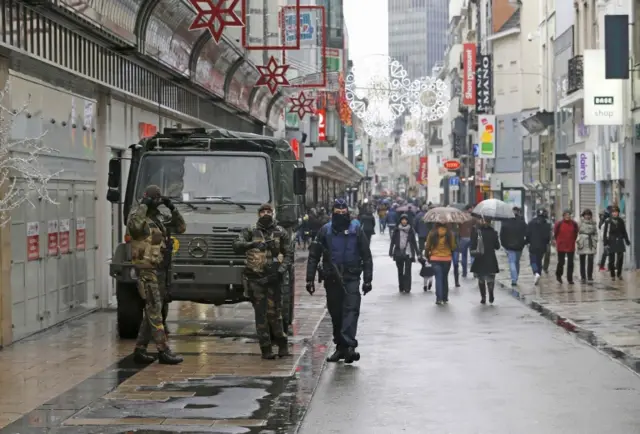 Belgian soldiers and a police officer patrol a shopping street in central Brussels