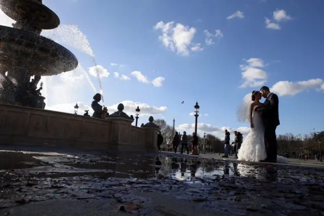 A married couple poses for pictures on the Place de la Concorde next to the Champs Elysees in Paris, France, 22 November