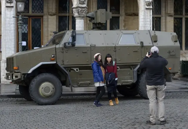 Tourists pose for a picture in front of an armoured vehicle on the Grand Place in Brussels