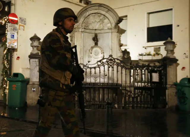 A Belgian soldier patriols past Brussels" famous Manneken-Pis statue as police search the area during a continued high level of security