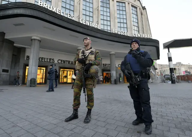 A Belgian policeman and a soldier stand guard outside the central station in Brussels