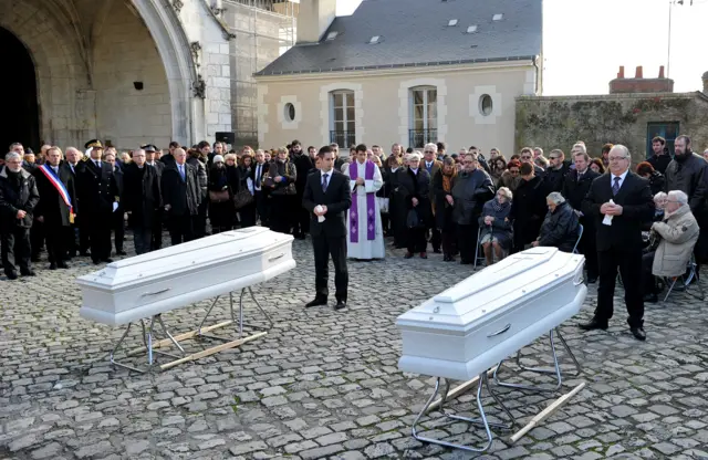 Friends and relatives gather in front of the coffins