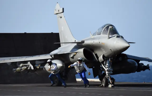 French navy soldiers prepare a French Rafale fighter aircraft before his flight with bombs off French aircraft carrier Charles-de-Gaulle, on 23 November 2015