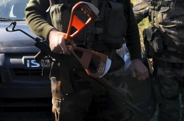 Alpaslan Celik, a deputy commander in a Syrian Turkmen brigade, holds handles believed to be parts of a parachute of the downed Russian warplane