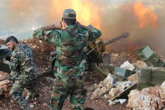 Syrian army personnel fire a cannon in Latakia province