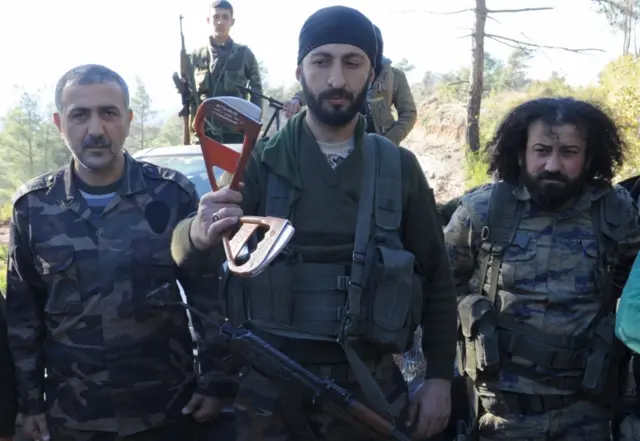 Alpaslan Celik, a deputy commander in a Syrian Turkmen brigade, holds handles believed to be parts of a parachute of the downed Russian warplane