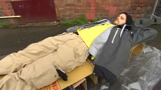 Homeless man trying out cardboard box bed