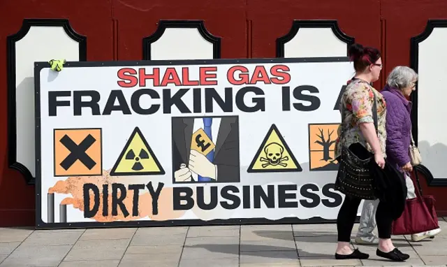 People walk past an anti-fracking banner as demonstrators outside Lancashire County Hall in Preston