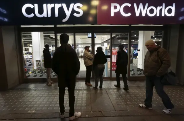 Shoppers wait outside Currys PC World