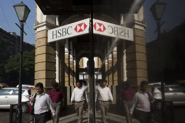 Pedestrians walk past a HSBC Holdings Plc bank branch in the Fort area of Mumbai