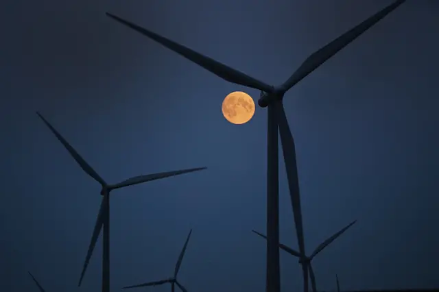 The moon rises behind the turbines of Whitelees Windfarm