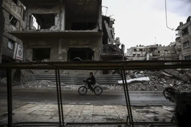 A young boy rides a bicycle in Douma, Syria