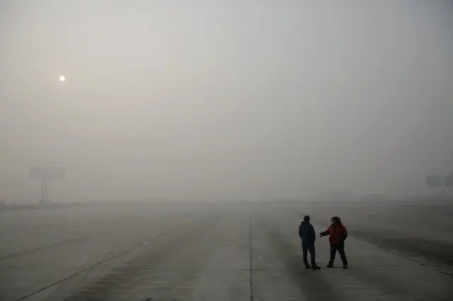 People talk behind a toll gate on a highway between Beijing and Hebei province