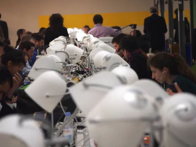 long line of occupied desks and desk lamps