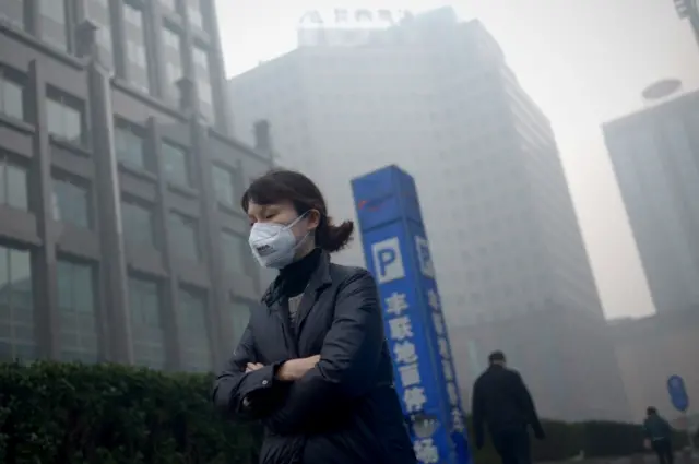 A woman wearing a mask walks past in Beijing on November 30, 2015.