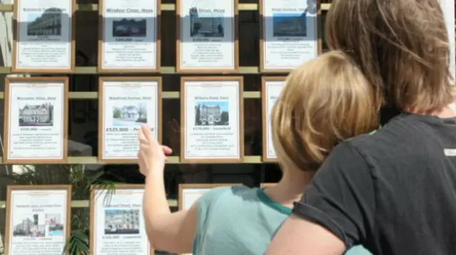 People looking at an estate agent's window