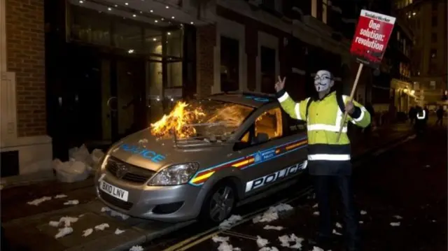 Protester with burning poilce car