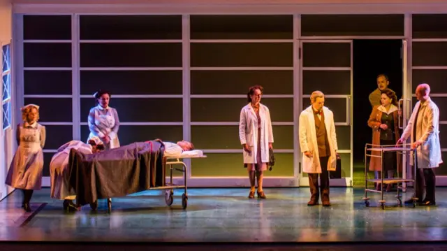 One patient on trolley surrounded by Doctors and Nurses with Angelica and Medoro entering the room via the door